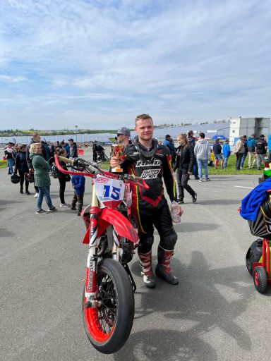 Benjamin Hagmaier mit seiner roten Supermoto und einem Pokal in der Hand